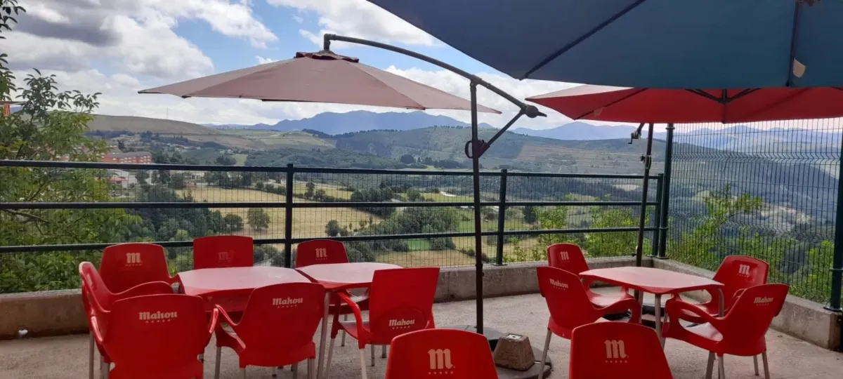 Terraza con sillas, mesas y sombrillas, y vistas al valle